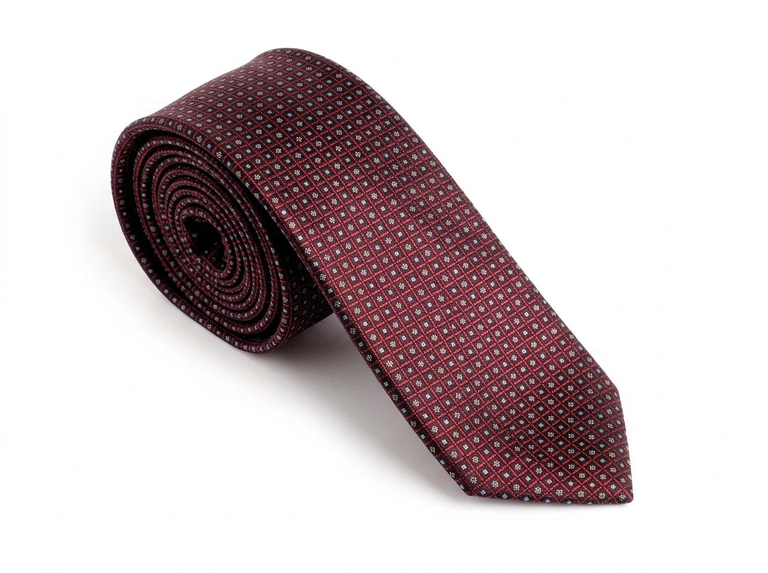 A rolled-up necktie in a deep burgundy or maroon color, featuring a small repeating geometric pattern in a lighter tone, set against a plain white background.
