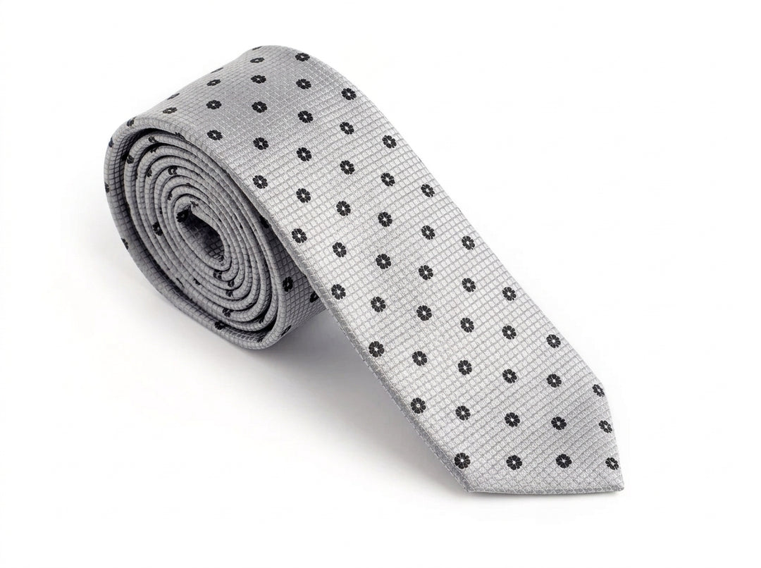A light gray silk necktie with a repeating pattern of small black embroidered dots, rolled up and displayed on a clean white background.