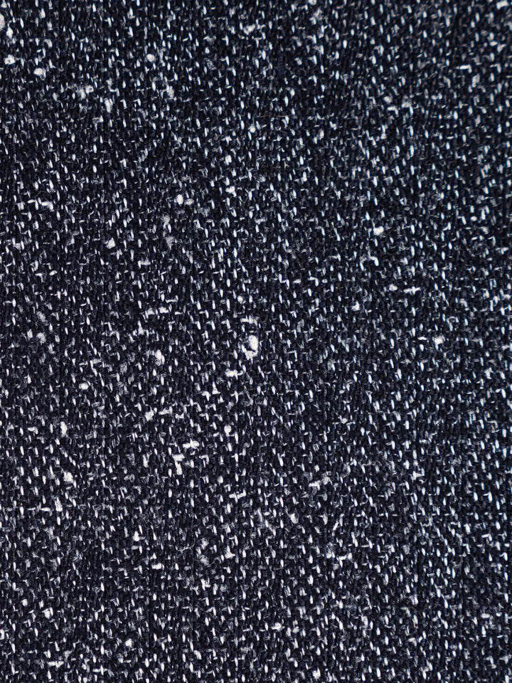 A close-up texture shot of a dark navy blue woven fabric with white flecks throughout, showing the detailed knit or woven pattern.