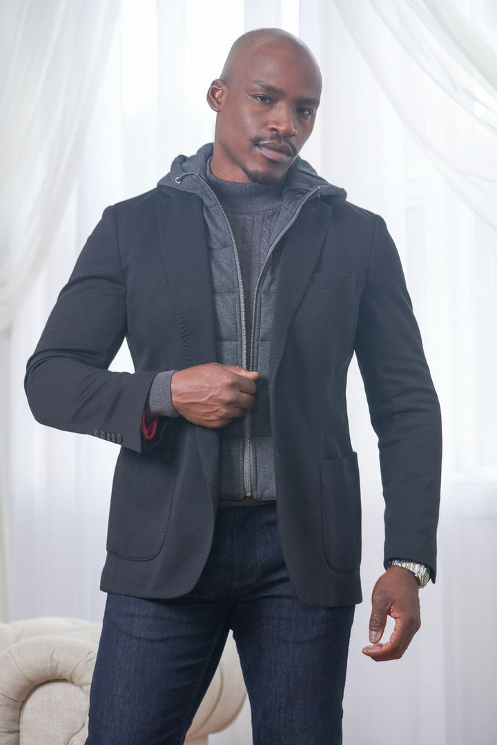 Man wearing a dark gray blazer over a gray shirt with a white background