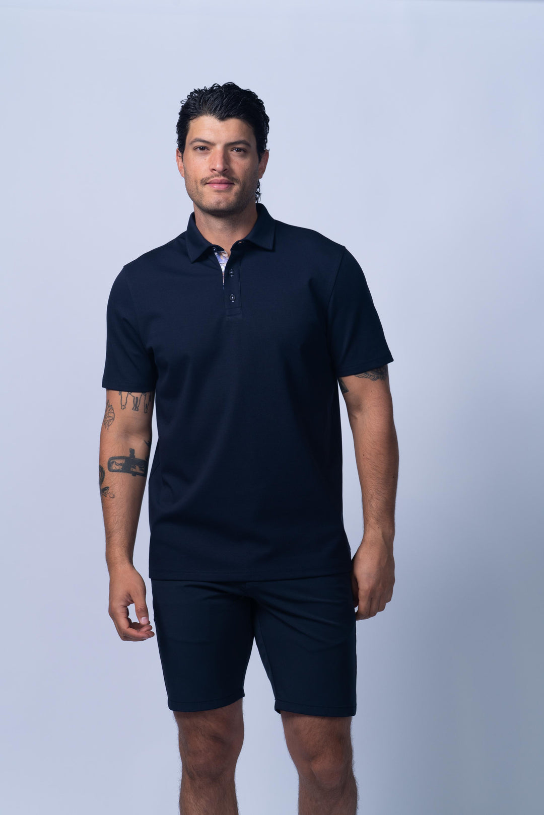 Man wearing a navy blue polo shirt and shorts