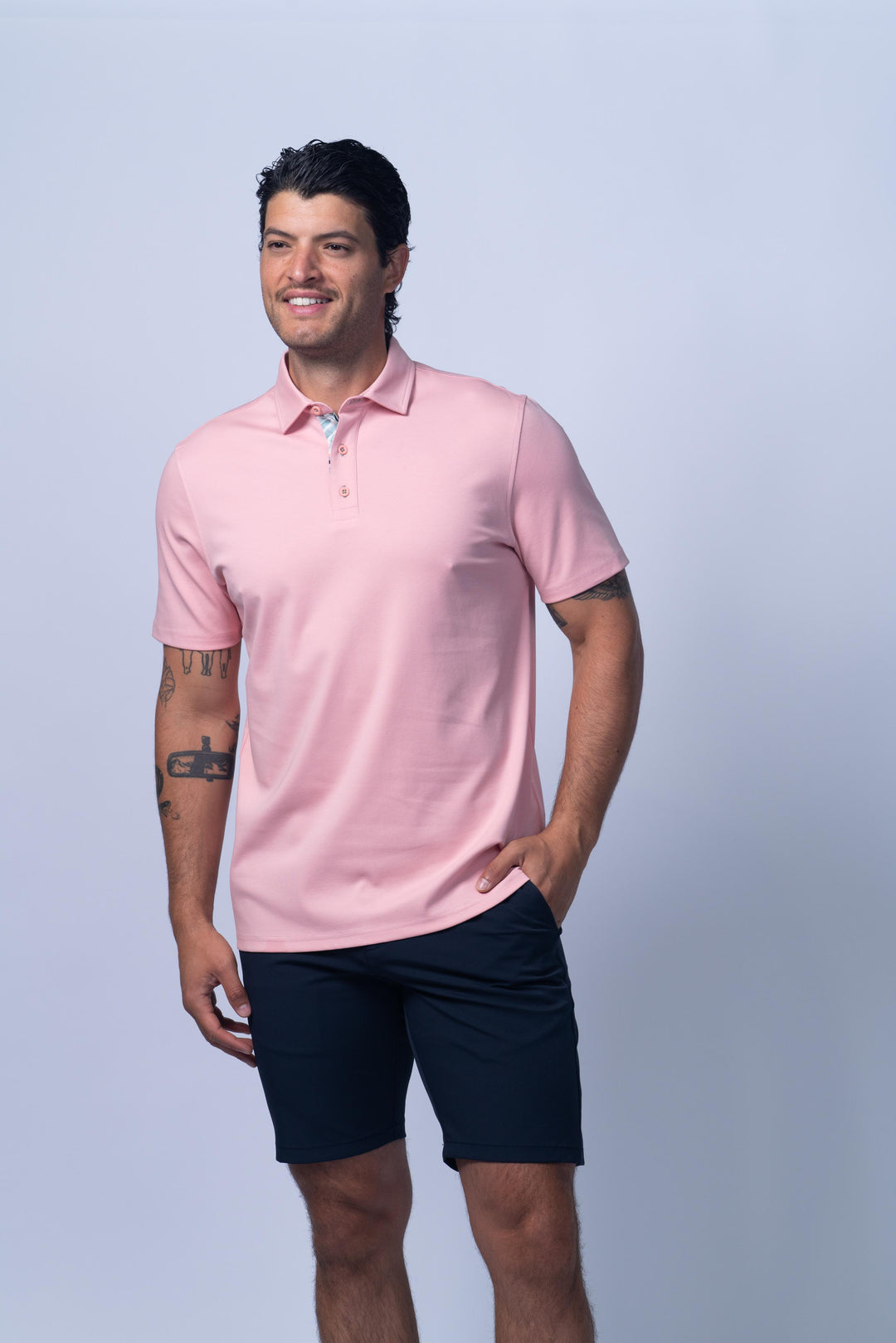 Man wearing a pink polo shirt and black shorts
