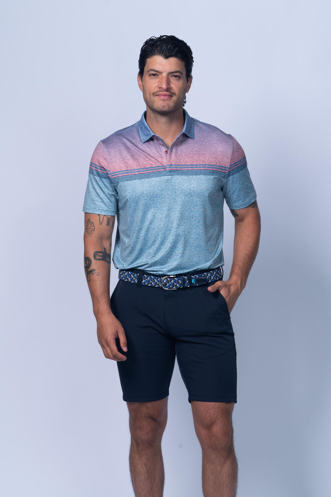 Man wearing a blue and pink striped polo shirt and navy shorts on a white background