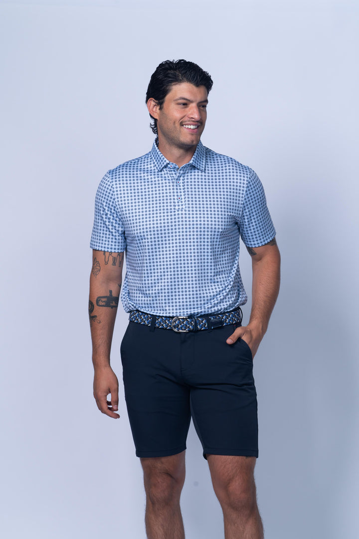 Man wearing a blue checkered shirt and navy shorts against a light gray background