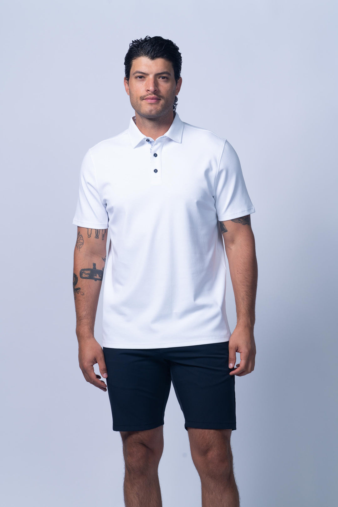 Man wearing a white polo shirt and dark shorts 