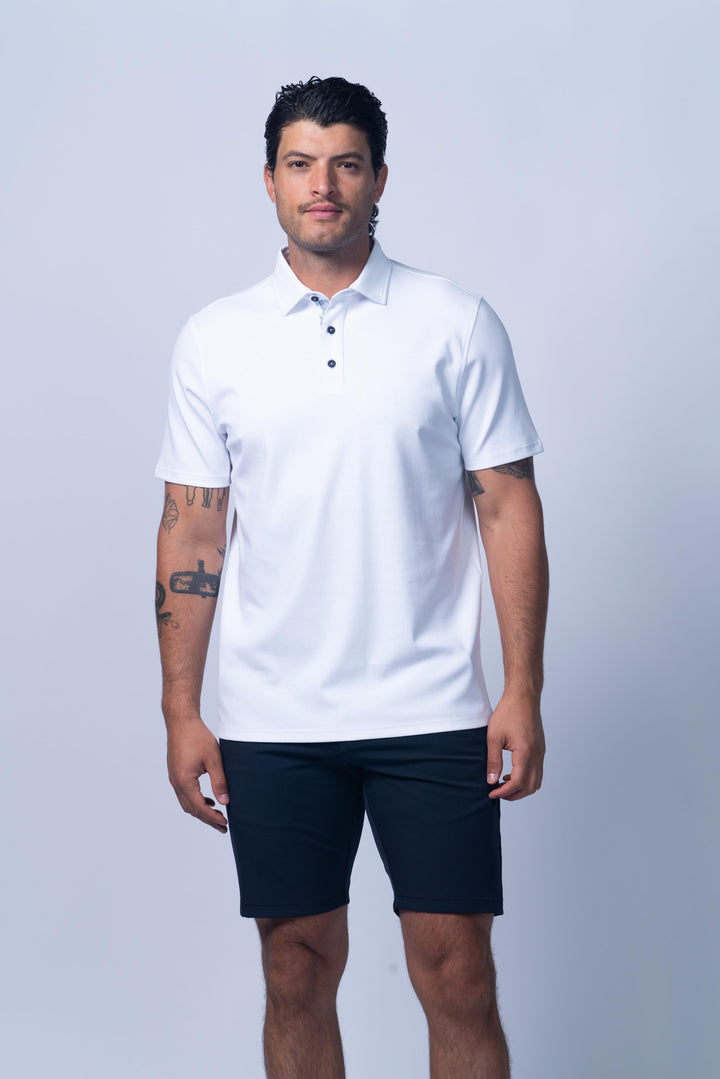 Man wearing a white polo shirt and dark shorts 