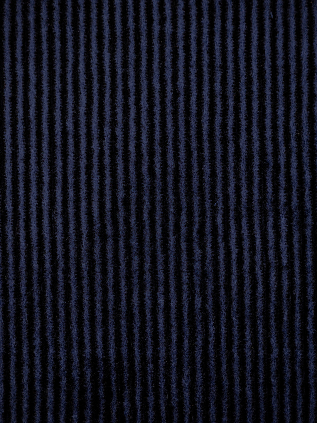 A close-up of a dark navy blue fabric with vertical textured stripes.