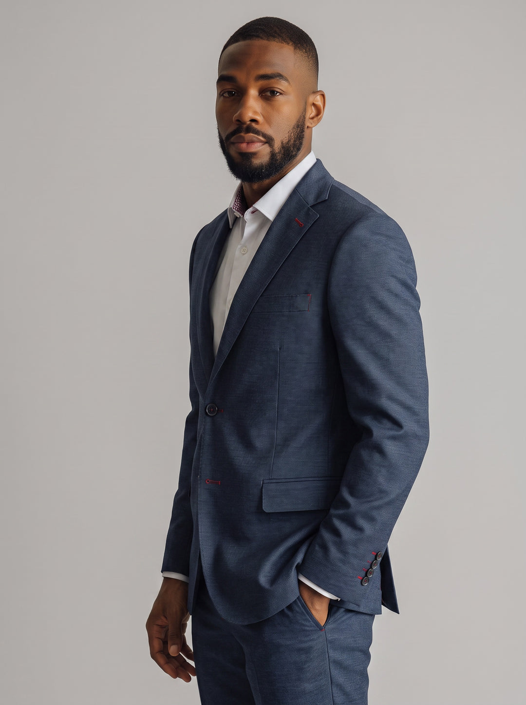 A man wearing a navy blue textured suit jacket and matching trousers over a white dress shirt