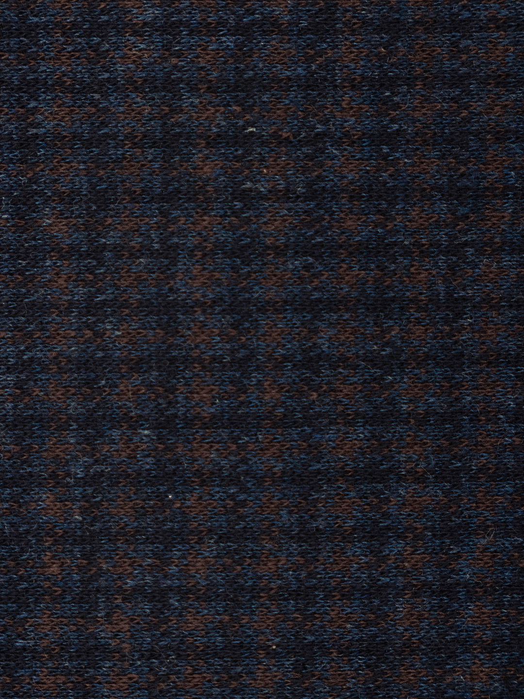 A close-up of a textured woven fabric with a dark navy blue and brown houndstooth pattern.