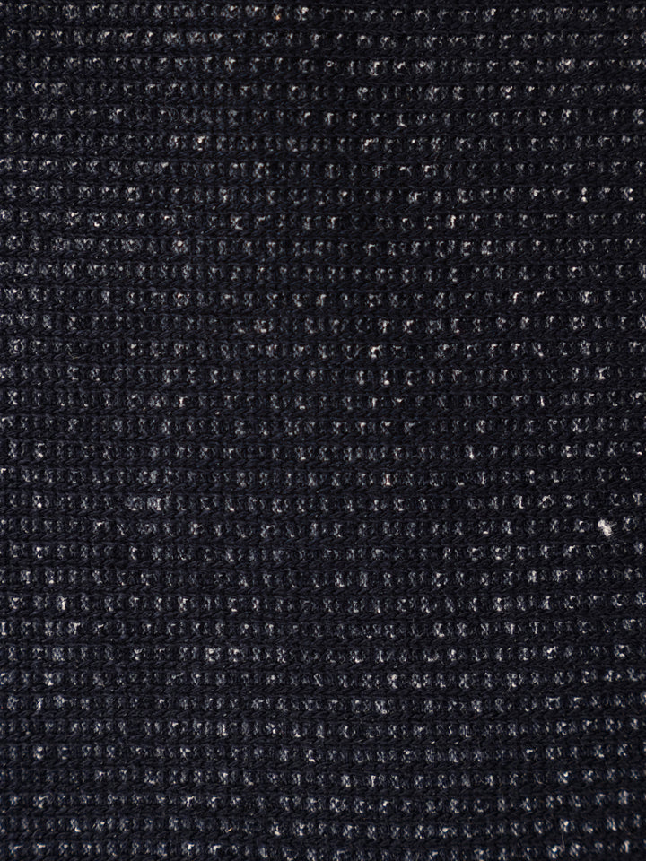 A close-up texture shot of a dark charcoal gray woven fabric, showing a detailed ribbed or waffle-like knit pattern.