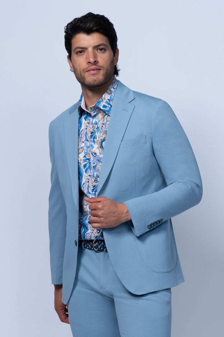 Man wearing a light blue suit with a patterned shirt 