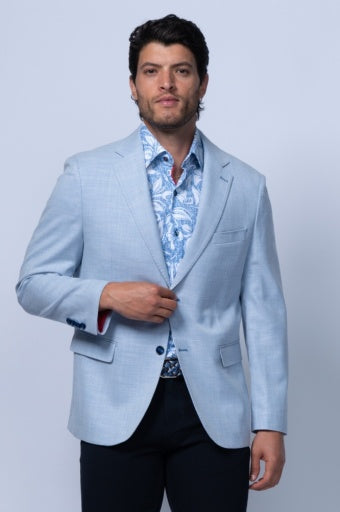 Light blue tailored blazer with notch lapel, styled over a patterned shirt and dark trousers.