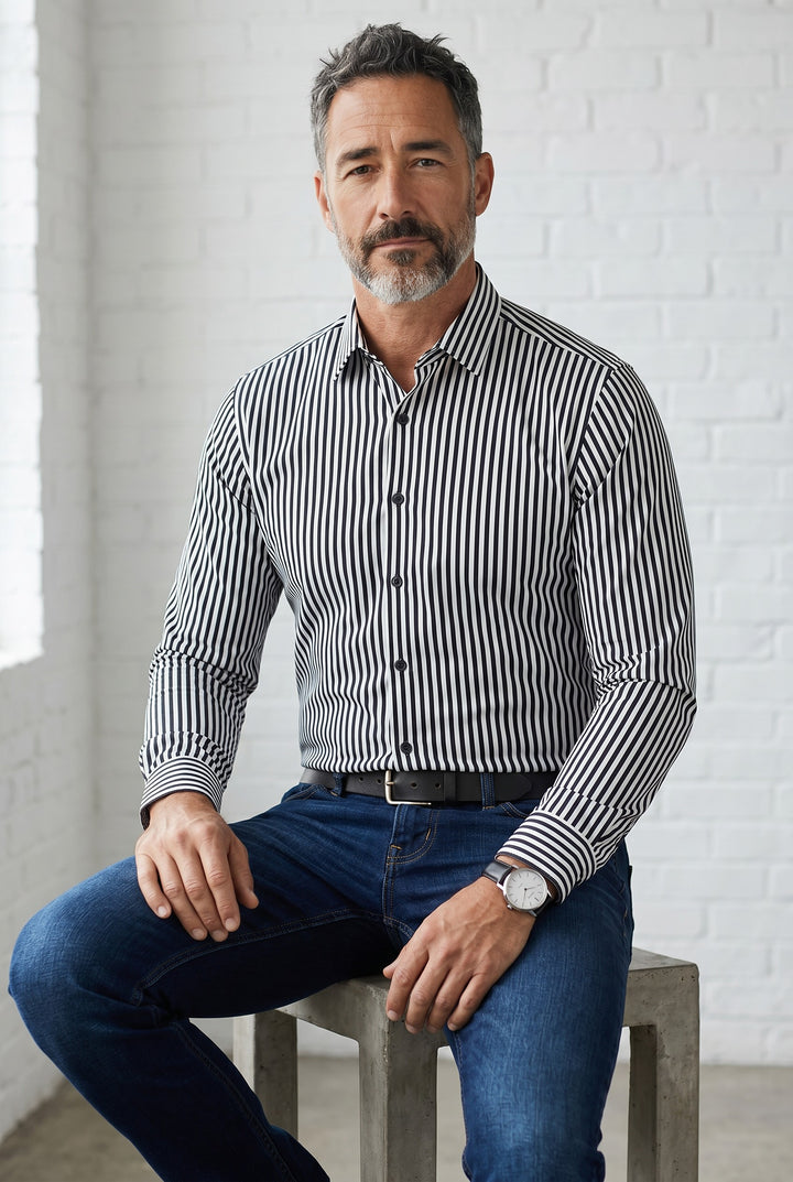Navy and white striped button-down shirt worn with blue jeans, set against a light brick wall.