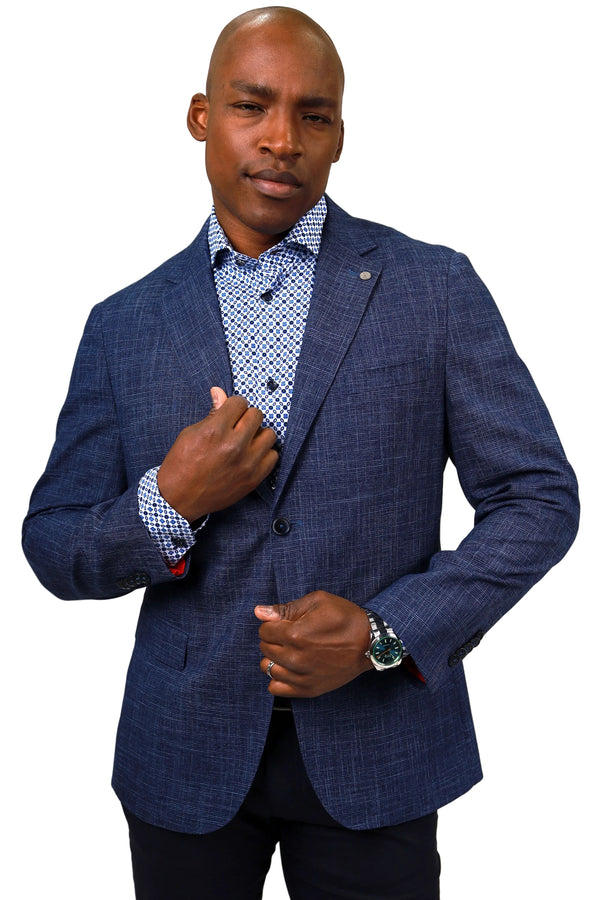 A man wearing a textured navy blue blazer over a blue and white patterned dress shirt, paired with dark trousers, photographed against a solid white background.