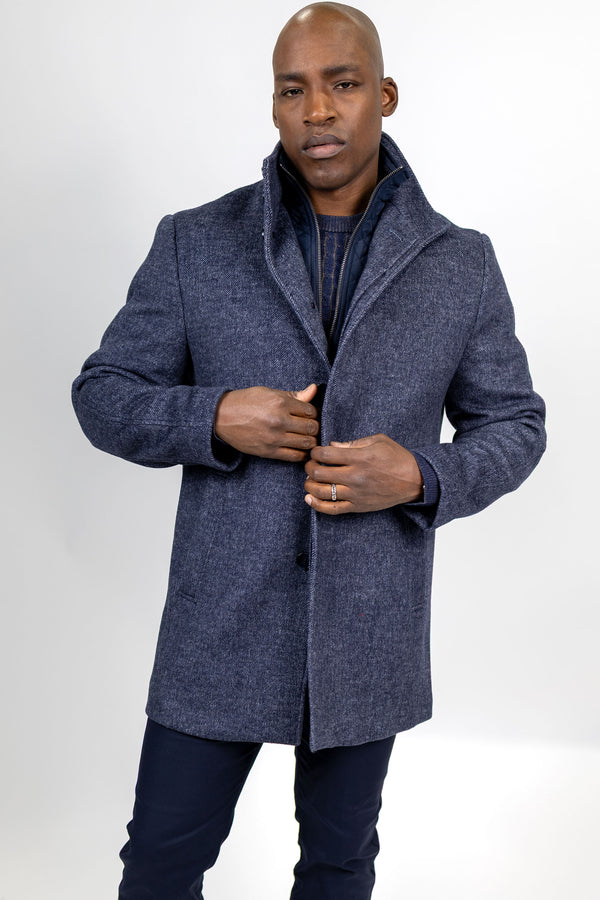 A man wearing a textured navy blue wool-blend coat with a high shawl collar.