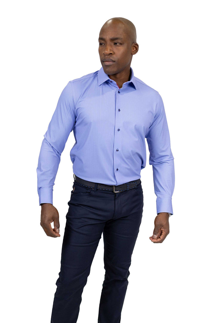 A man wearing a light blue long-sleeve button-down dress shirt and dark navy trousers, standing against a plain white background.